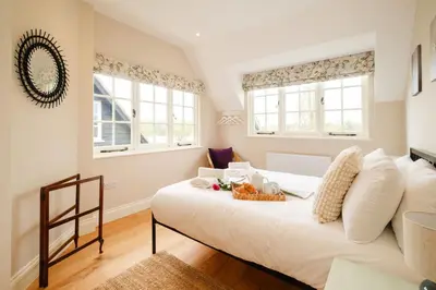 a bedroom with a large white bed and two windows at 9 The Haven in Thorpeness