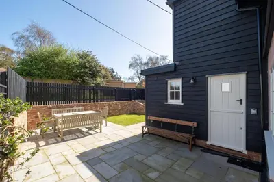 a black house with a bench and a white door at 9 The Haven in Thorpeness
