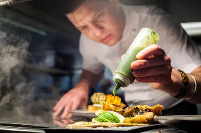 a chef is preparing food on a grill at Noble Goose Rooms in Coggeshall