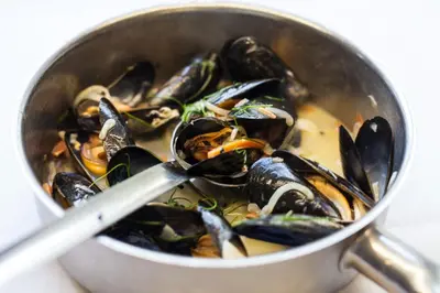 a pot of mussels with a spoon in it at Noble Goose Rooms in Coggeshall