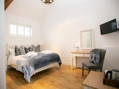 a bedroom with a bed and a desk and a chair at Great Blunts Stables - Stock Brook Manor Golf Club in Billericay