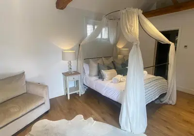 a bedroom with a canopy bed and a couch at Great Blunts Stables - Stock Brook Manor Golf Club in Billericay