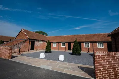 a brick building with two white benches in the courtyard at Great Blunts Stables - Stock Brook Manor Golf Club in Billericay