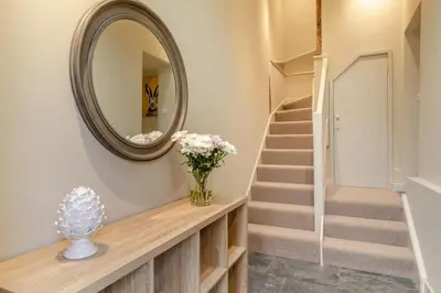 a hallway with a mirror and a staircase with a vase of flowers at 2 Bed in Heveningham oc-w29035 in Heveningham