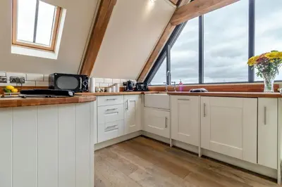 a kitchen with white cabinets and large windows at 1 Bed in Heveningham oc-w29032 in Heveningham