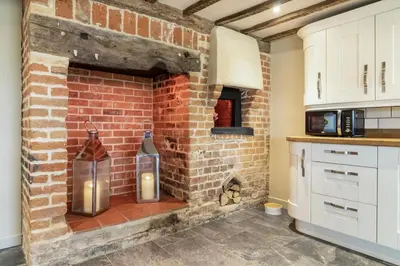 a brick fireplace in a kitchen with two candles at 2 Bed in Heveningham oc-w29034 in Heveningham