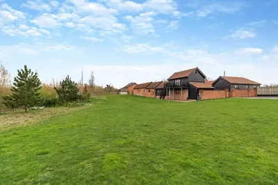 a large grassy field with a row of houses at 3 Bed in Heveningham oc-w29031 in Heveningham