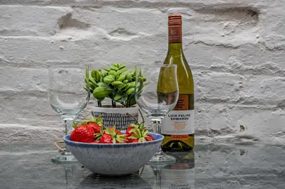 a bottle of wine and two wine glasses and a bowl of fruit at 3 Bed in Aldeburgh oc-o5630 in Aldeburgh