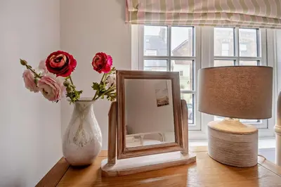 a mirror and a vase with flowers on a table at 3 Bed in Aldeburgh oc-o5630 in Aldeburgh