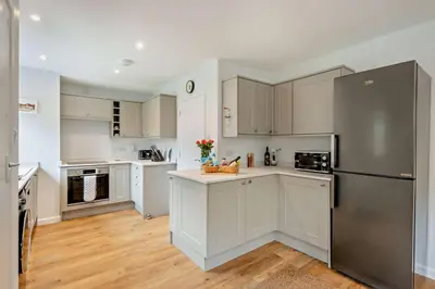 a kitchen with white cabinets and a stainless steel refrigerator at 3 Bed in Acton oc-c28929 in Great Waldingfield