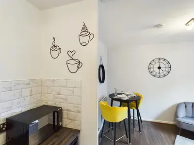 a dining room with a table and a small table with yellow chairs at Cosy Modern Apartment Colchester in Colchester