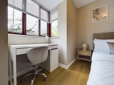 a bedroom with a desk and a bed with windows at Cosy Modern Apartment Colchester in Colchester