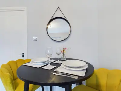a black table with yellow chairs and a mirror at Cosy Modern Apartment Colchester in Colchester