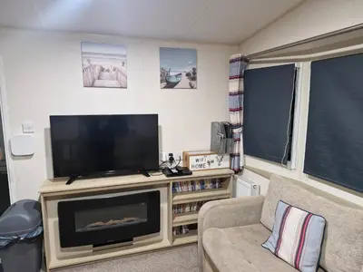 a living room with a flat screen tv on a entertainment center at Highfield Grange Holiday Park in Little Clacton