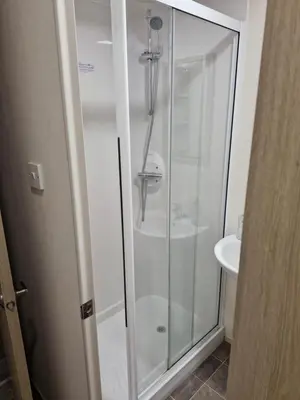 a glass shower in a bathroom with a sink at Highfield Grange Holiday Park in Little Clacton