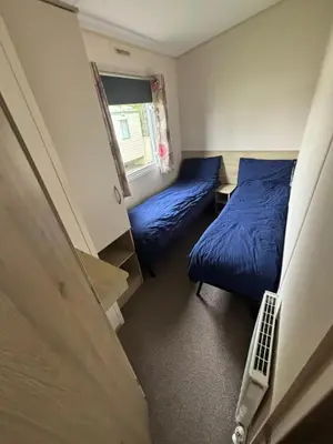 a small room with two beds and a window at Highfield Grange Holiday Park in Little Clacton