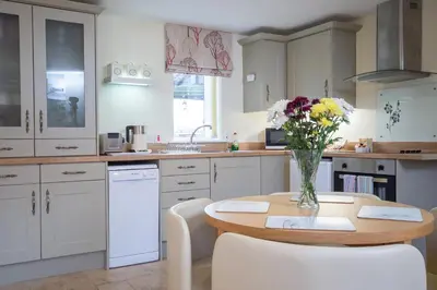 a kitchen with a table with a vase of flowers on it at Mollett's Farm in Saxmundham