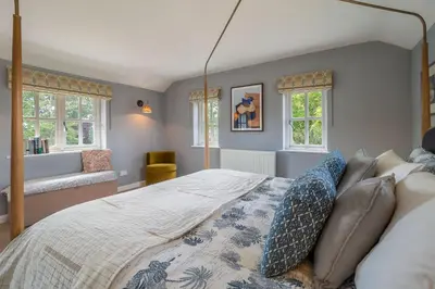 a bedroom with a large bed and windows at Foxhole Cottage 8 in Stowmarket