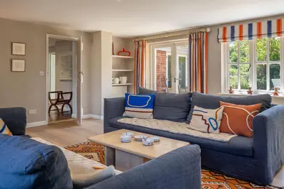 a living room with a blue couch and a table at Foxhole Cottage 10 in Stowmarket