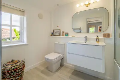 a white bathroom with a toilet and a mirror at Foxhole Cottage 10 in Stowmarket