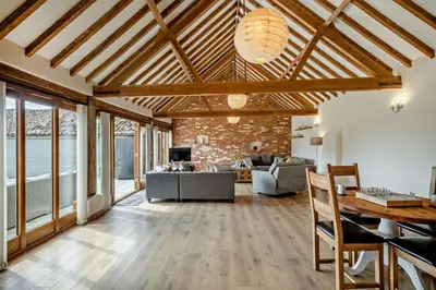 a living room with wooden ceilings and a brick wall at 4 Bed in Barnham Broom oc-b27788 in Kimberley