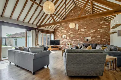 a living room with couches and a brick wall at 4 Bed in Barnham Broom oc-b27788 in Kimberley