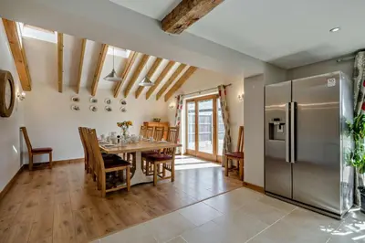 a kitchen and dining room with a table and a refrigerator at 4 Bed in Barnham Broom oc-b27788 in Kimberley