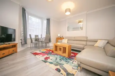 a living room with a couch and a tv and a table at Beautiful Ground Floor Victorian Apartment in Clacton-on-Sea