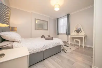 a bedroom with a large bed and a table at Beautiful Ground Floor Victorian Apartment in Clacton-on-Sea