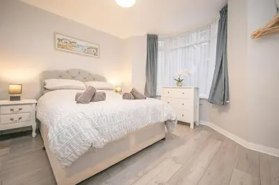 a bedroom with a large bed and a window at Beautiful Ground Floor Victorian Apartment in Clacton-on-Sea