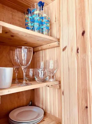 a wooden cabin with wine glasses and plates on shelves at The Hideout in Linton