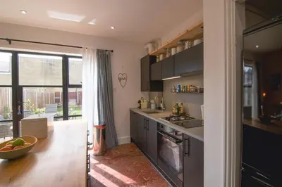 a kitchen with black cabinets and a large window at Cosy Stylish house near Southend - Pass the Keys in Southend-on-Sea