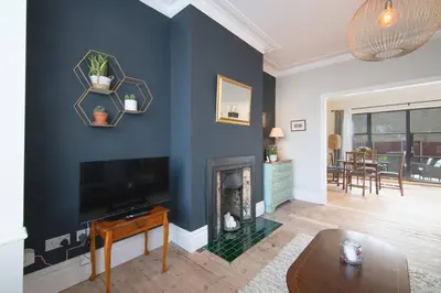 a living room with a blue wall with a fireplace at Cosy Stylish house near Southend - Pass the Keys in Southend-on-Sea