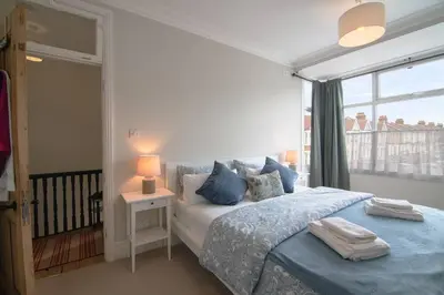 a bedroom with a bed with blue pillows and a window at Cosy Stylish house near Southend - Pass the Keys in Southend-on-Sea