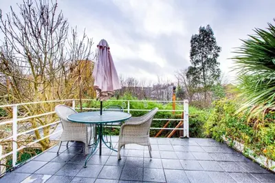 a patio with a table and chairs and an umbrella at Entire studio with private parking and balcony in Southend-on-Sea