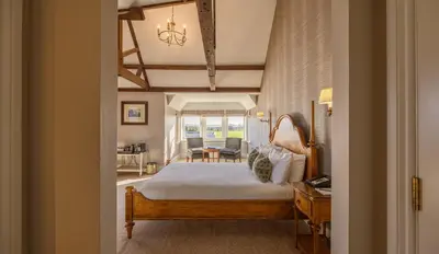 a bedroom with a bed and a desk and a chair at Wivenhoe House Hotel in Colchester