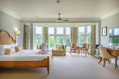 a bedroom with a bed and a desk and chairs at Wivenhoe House Hotel in Colchester