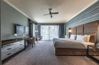 a bedroom with a bed and a desk and a television at Wivenhoe House Hotel in Colchester