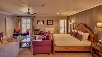 a bedroom with a bed and a couch and a table at Wivenhoe House Hotel in Colchester