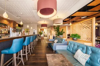 a bar with blue leather seats in a restaurant at Wivenhoe House Hotel in Colchester
