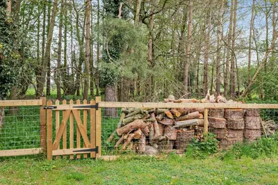 a wooden fence with a pile of logs behind it at 2 Bed in Eccles oc-l27507 in Eccles