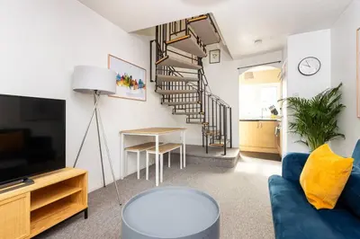 a living room with a blue couch and a spiral staircase at Beautiful House by Station with Private Parking in Cambridge