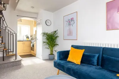 a living room with a blue couch and a kitchen at Beautiful House by Station with Private Parking in Cambridge