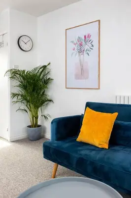 a blue couch with a yellow pillow in a living room at Beautiful House by Station with Private Parking in Cambridge