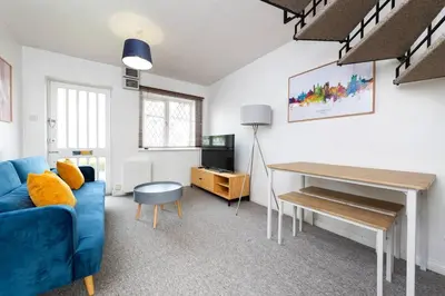 a living room with a blue couch and a desk at Beautiful House by Station with Private Parking in Cambridge