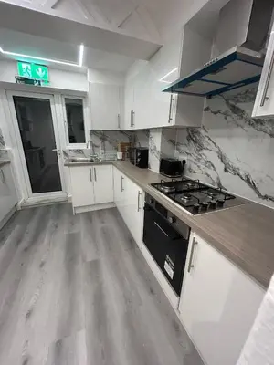 a kitchen with white cabinets and a stove top oven at Welcoming Guesthouse in Cambridge