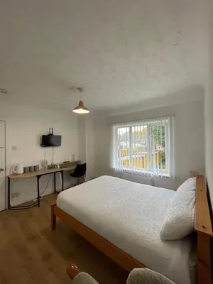 a bedroom with a bed and a desk and a window at Welcoming Guesthouse in Cambridge