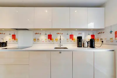 a white kitchen with white cabinets and a sink at Pass the Keys 53 Austin Drive · Modern Townhouse near Addenbrookes Own Parking in Cambridge