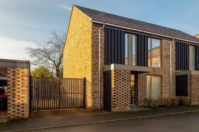 a brick house with a gate and a fence at Pass the Keys 53 Austin Drive · Modern Townhouse near Addenbrookes Own Parking in Cambridge