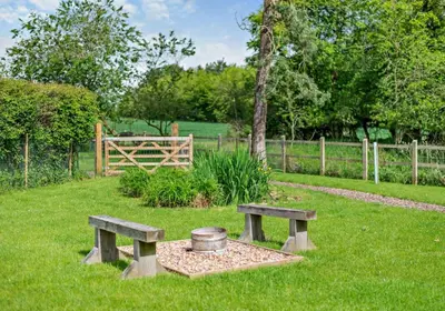 two benches in the grass with a wooden fence at Luxury Silver Birch Lodge: Hot Tub/BBQ/Fire Pit in Toppesfield
